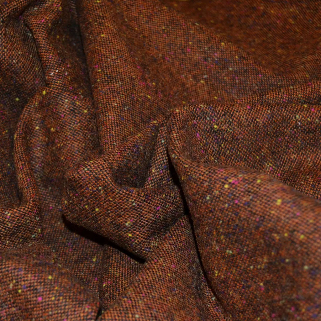 Close-up of Donegal tweed fabric, featuring its characteristic multicolored speckled pattern and textured wool surface, ideal for traditional garments and stylish home decor.