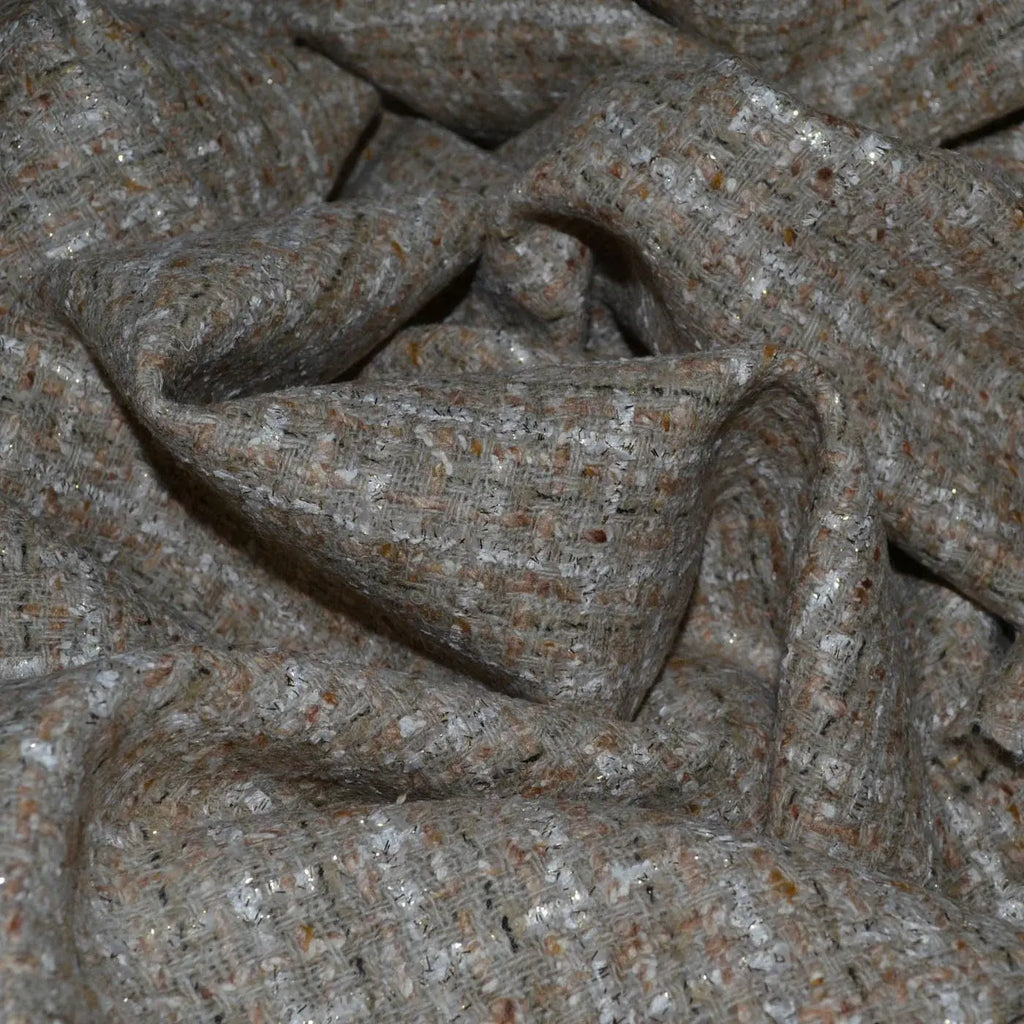 Close-up of boucle fabric, showcasing its textured, nubby surface with small loops, perfect for creating cozy garments and stylish home decor.